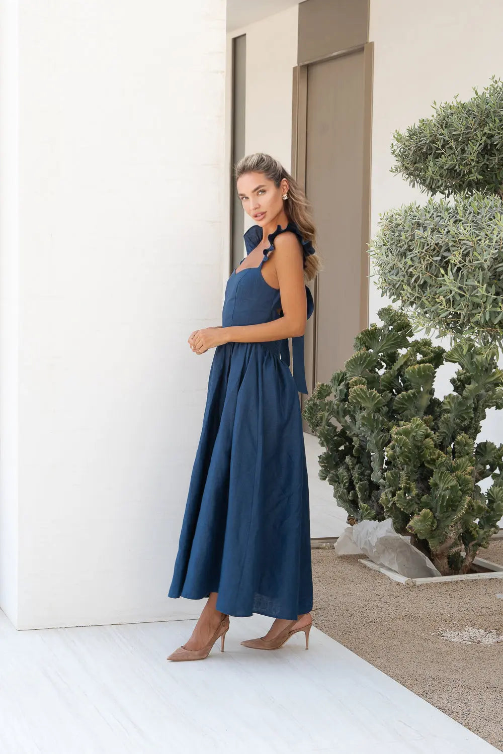 Elegant blue The Aurelia Dress by Anne Louise Boutique displayed on a hanger with intricate lace details and flowing fabric.